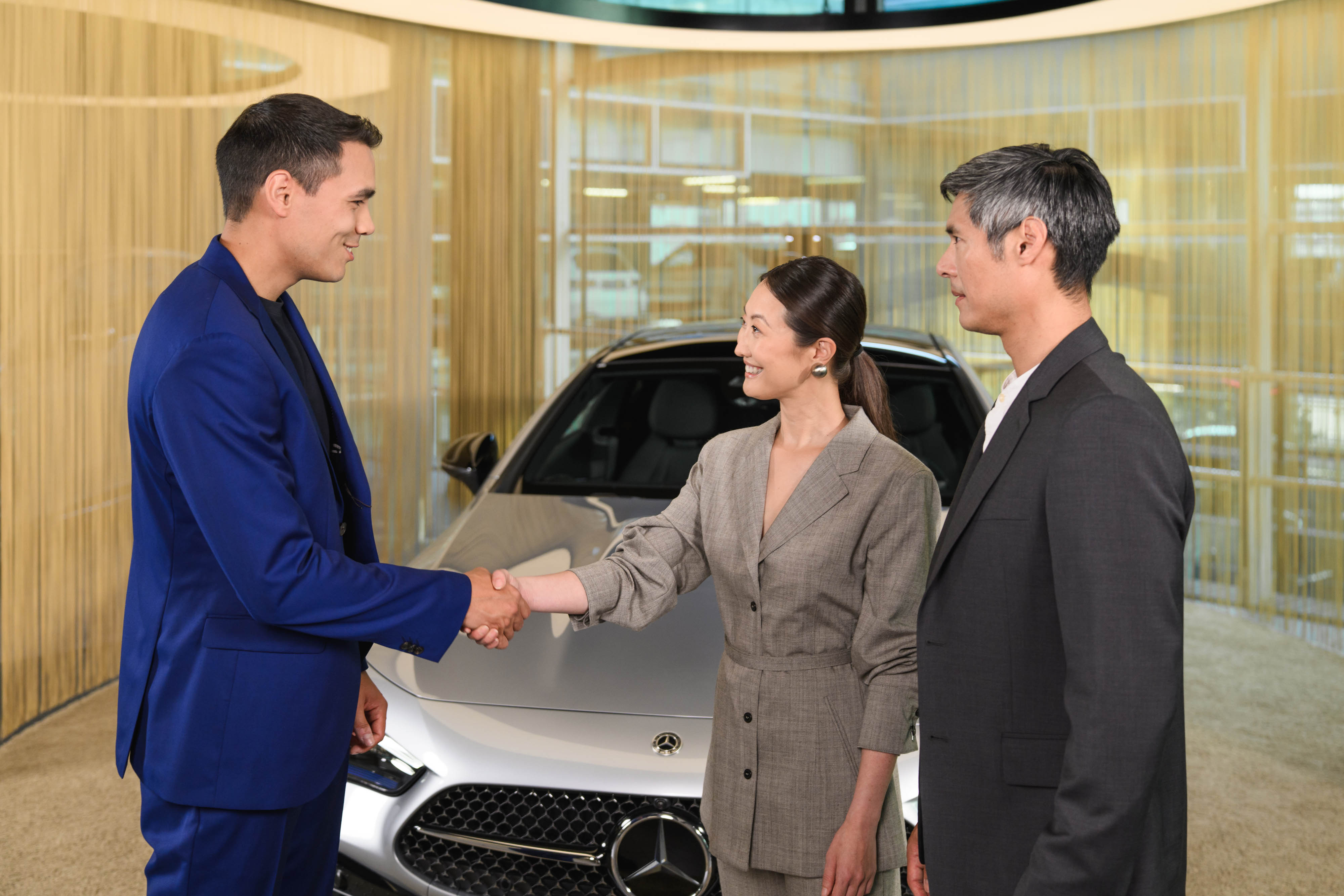 2018 Financial Services Photo Shooting "Couple" Drei Personen stehen vor einem Mercedes-Benz Fahrzeug und schüteln sich die Hände.