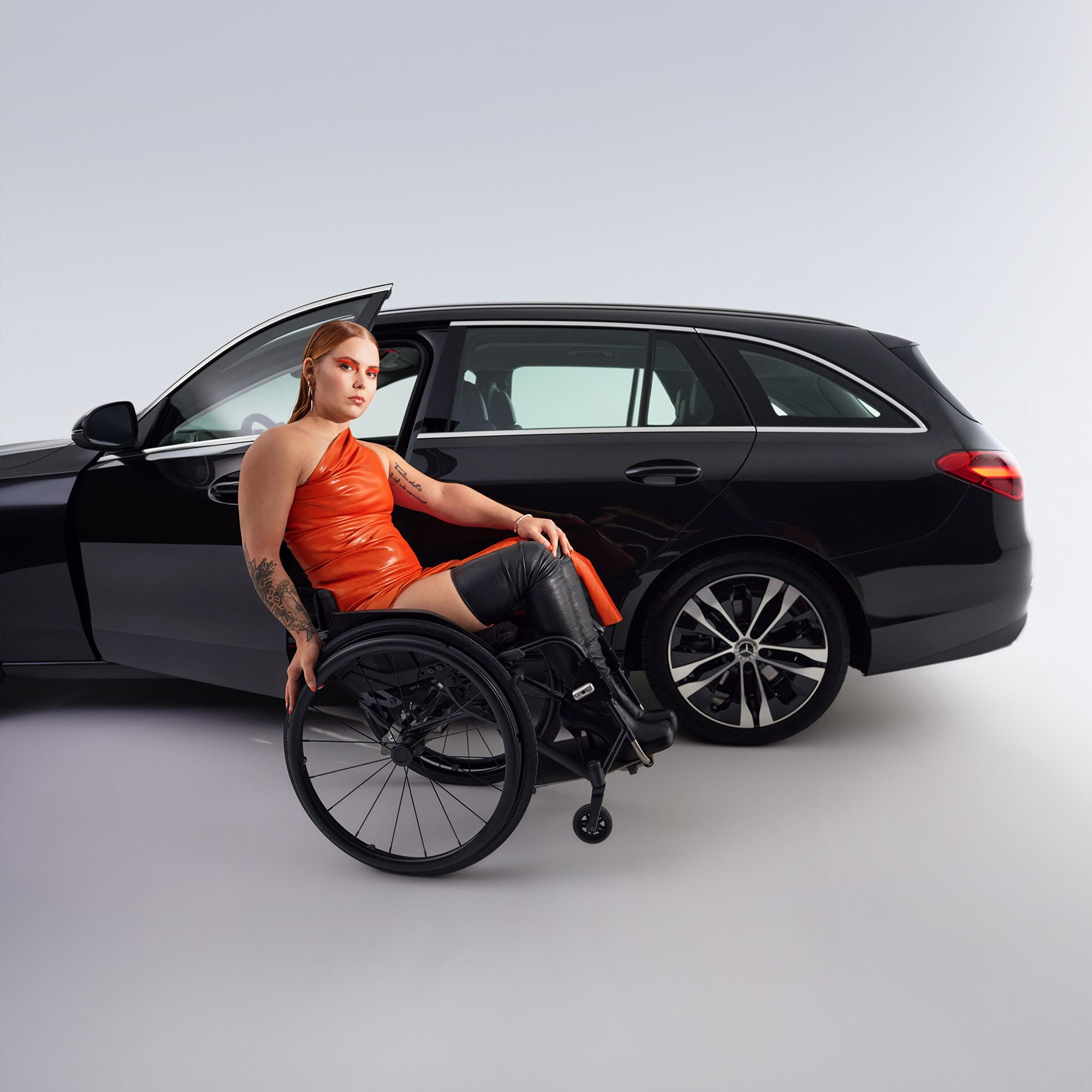 Ein- und Ausstiegshilfen | Fahrhilfen | Mercedes-Benz Das behindertengerecht umgebaute C-Klasse T-Modell in einer Seitenansicht und eine Frau im Rollstuhl.