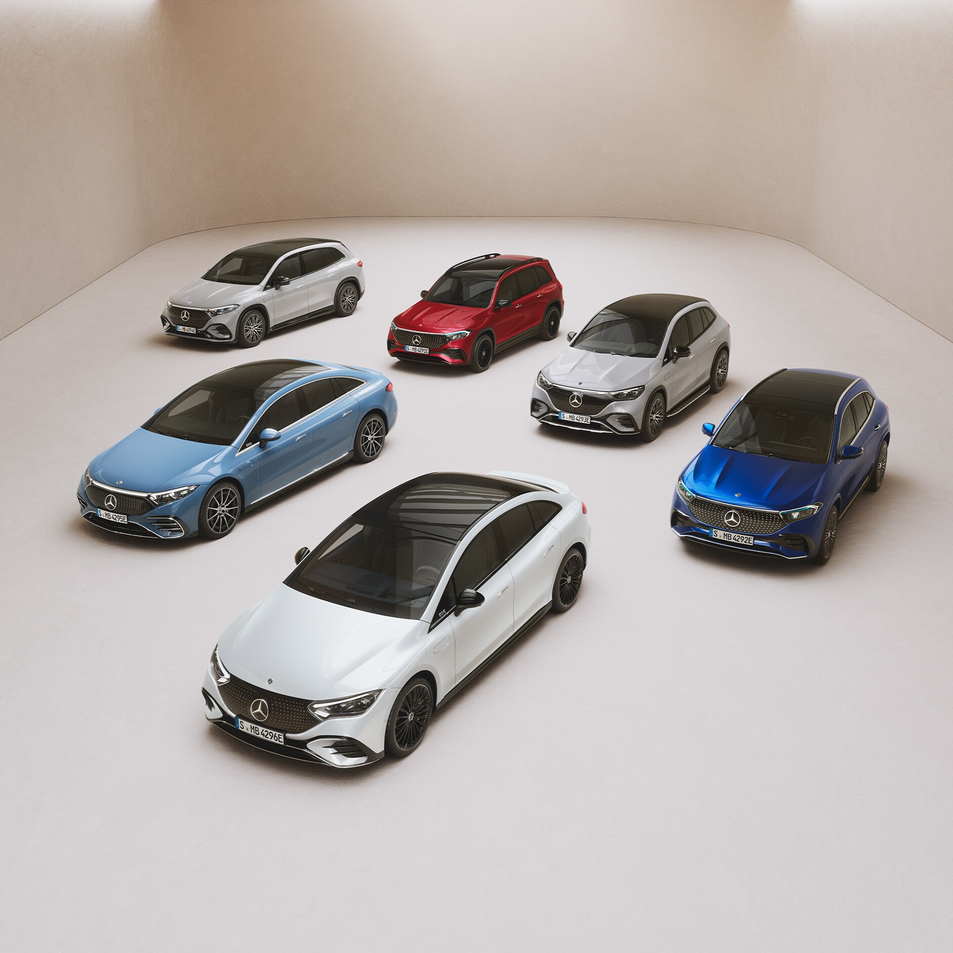 Die Modelle der EQ-Reihe von Mercedes-Benz. Die Modelle EQS Limousine, EQE Limousine, EQA, EQB und EQC stehen geparkt auf einer Spiegelfläche.